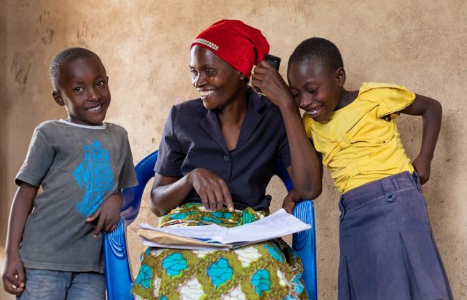 Jema Adamu, a woman living with HIV, and peer educator, helping son Jacksomi and grand daughter Faraja with school work. Nkuhungu, Dodoma, Tanzania, 4 October 2019 Credit: UNAIDS Jema Adamu, a woman living with HIV, and peer educator, helping son Jacksomi and grand daughter Faraja with school work. Nkuhungu, Dodoma, Tanzania, 4 October 2019 Credit: UNAIDS